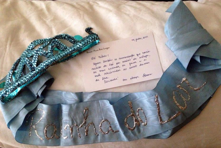 Faixa e coroa confeccionadas por Hildete Pereira. Com elas Carmen desfilou na passeata de 8 de maro de 1983, incorporando a personagem "A rainha do lar"! na mo direita um espanador, na esquerda um "Cesto de Vida", com utenslios domsticos. Foto de Eunice Gutman, confiada ao Acervo Carmen da Silva